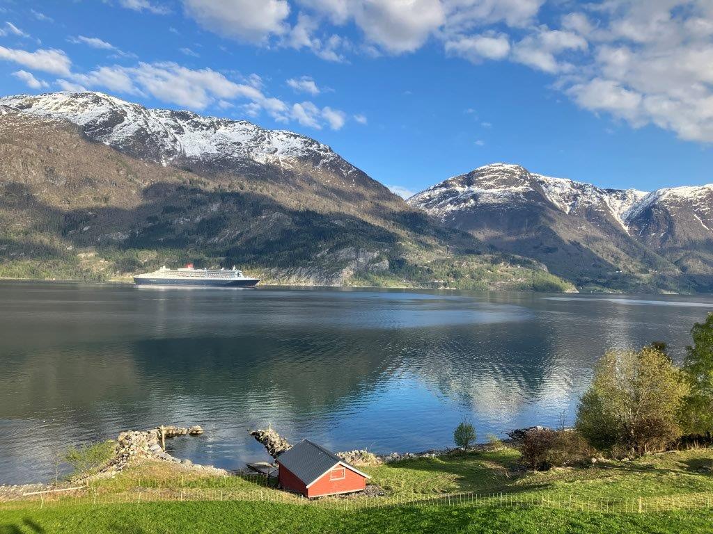 Motiv frå Lustrafjorden. Speilblank fjord med snødekte toppar og eit cruiseskip. Fotograf: Vegard Bondevik Lie